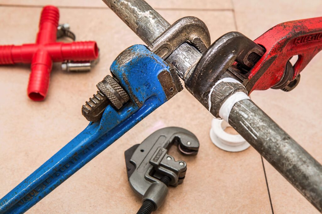 A pair of wrenches sits on a pipe.