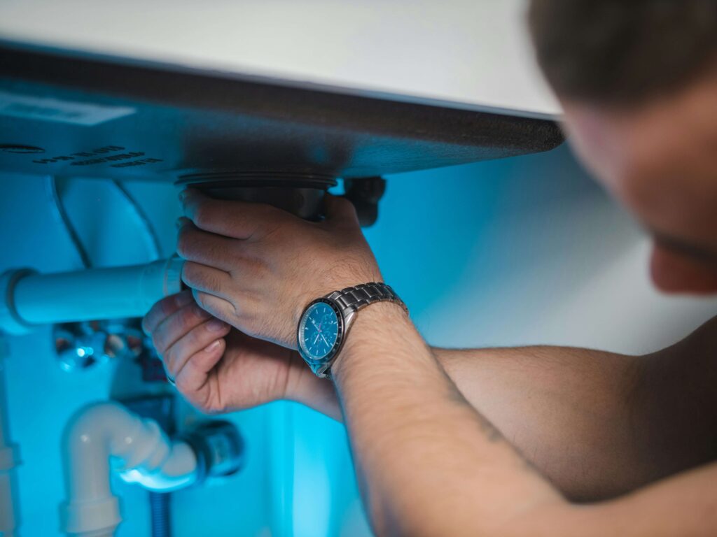 A plumber fixes a pipe.